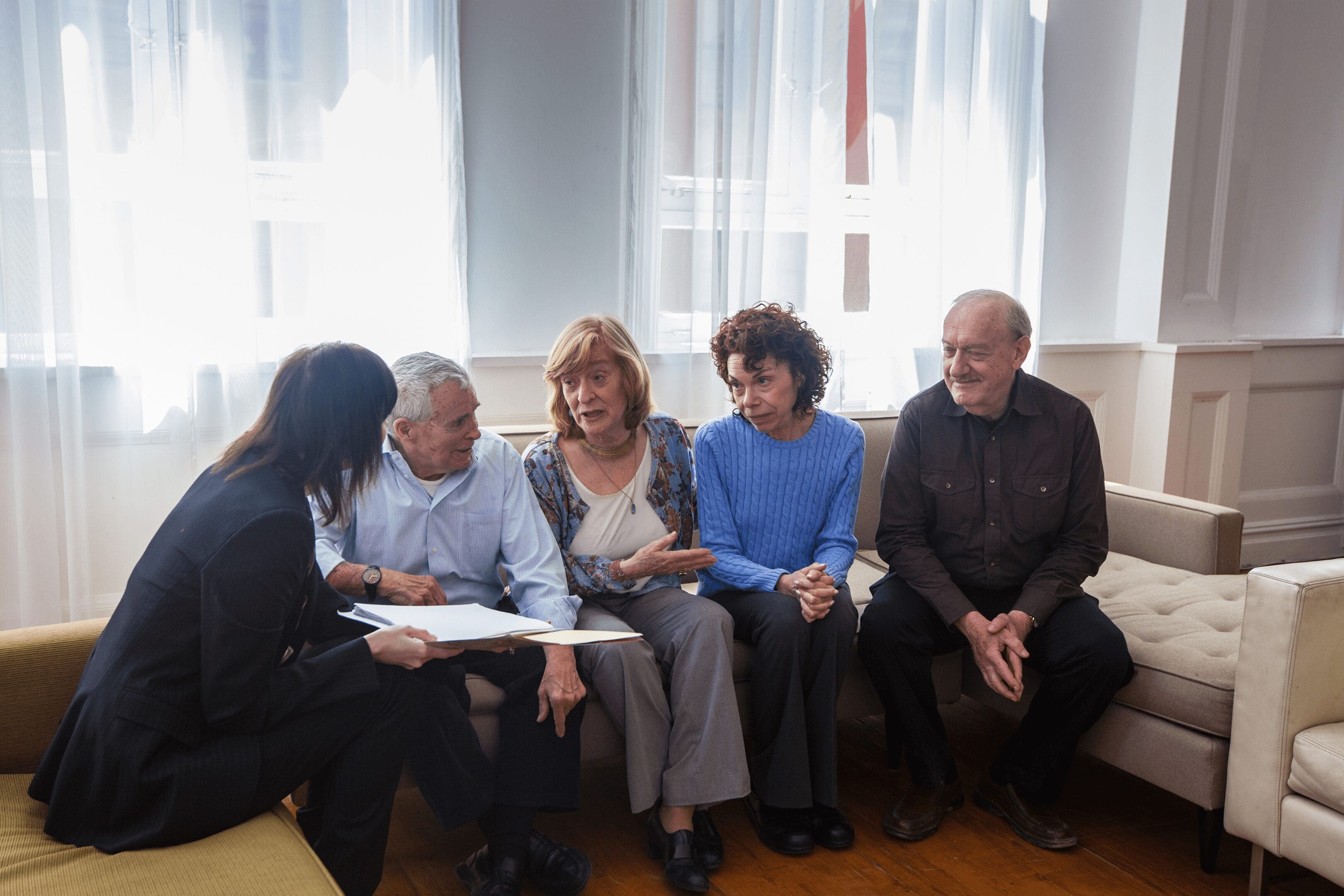 Seniors discussing paperwork with advisor on couch