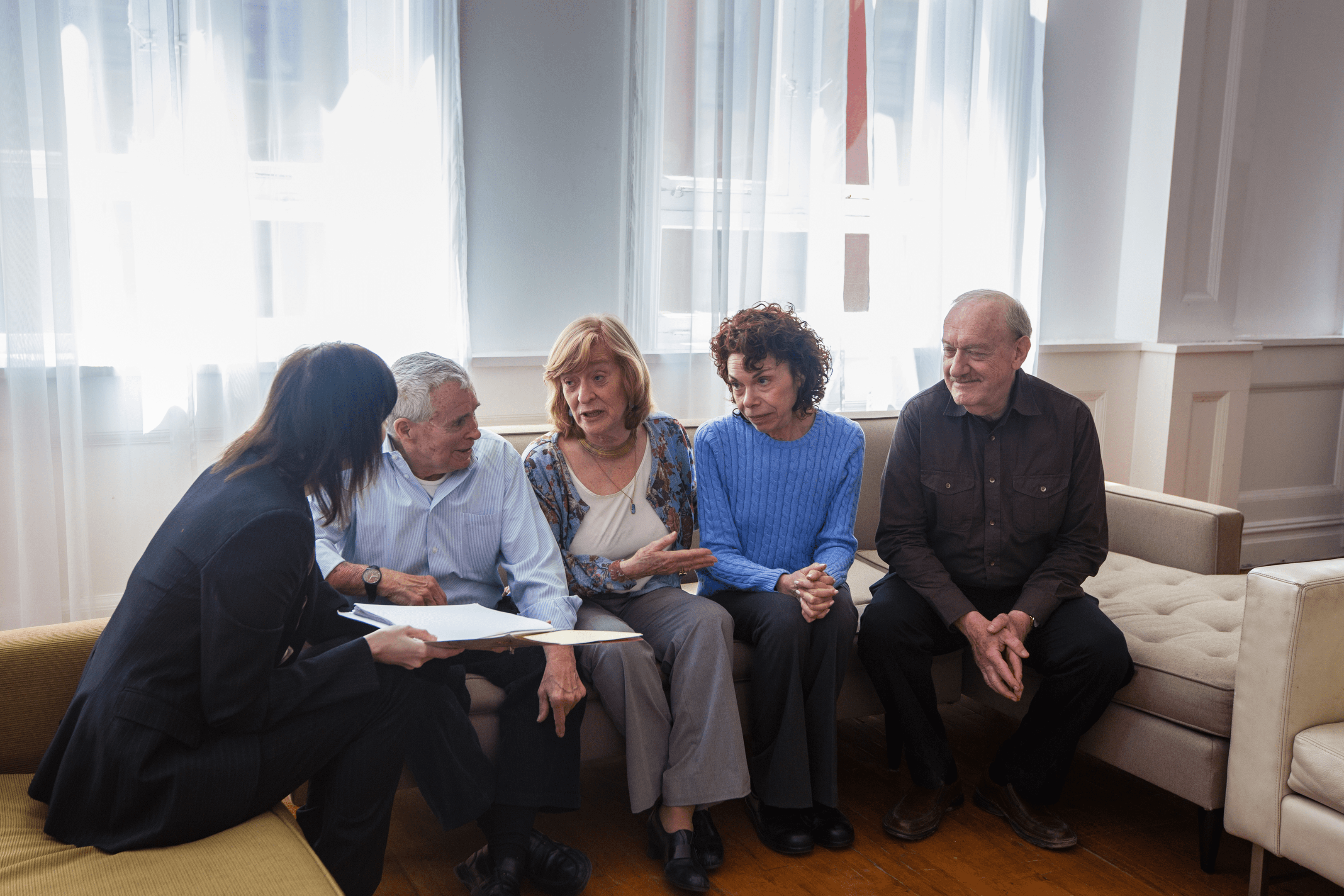 Seniors discussing paperwork with advisor on couch