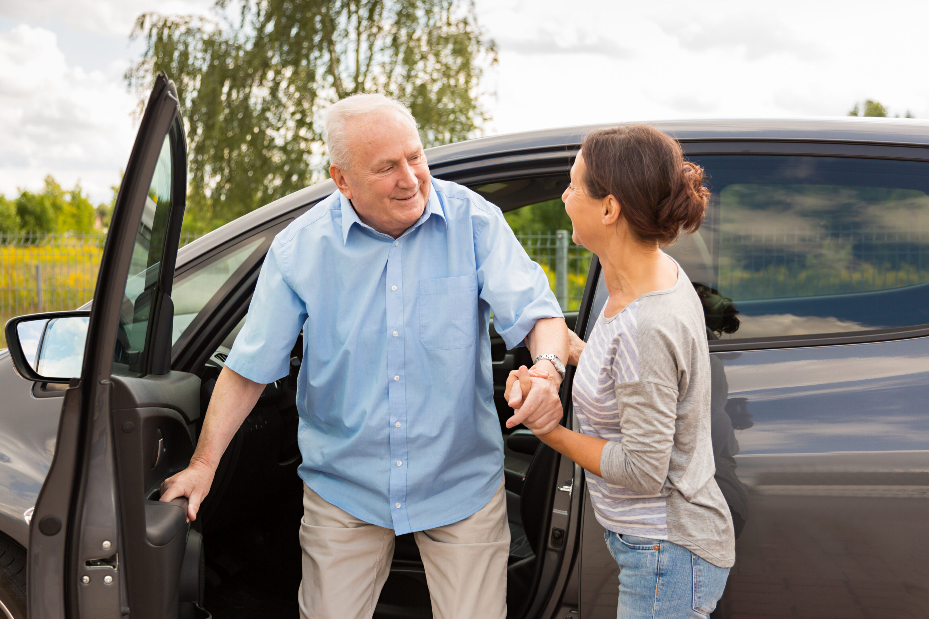 Woman helping elderly man out of car