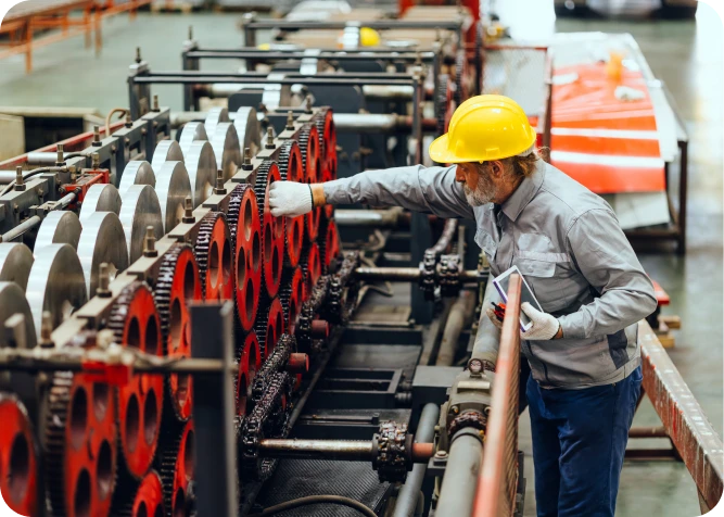 Worker inspecting machinery in industrial setting.